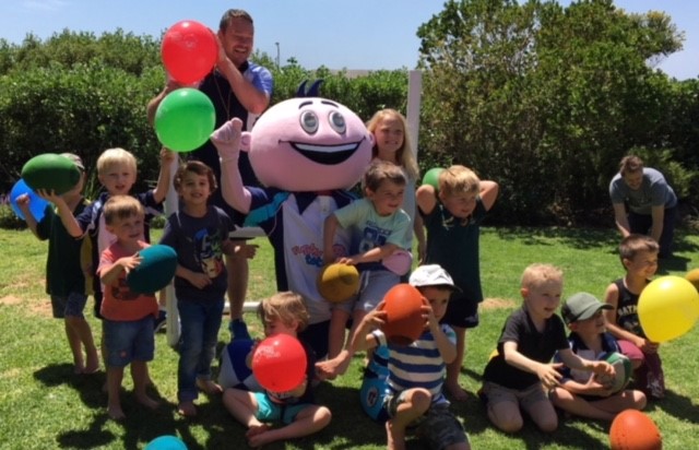 Group of smiling children holding party balloons and rugby balls for kids rugby party